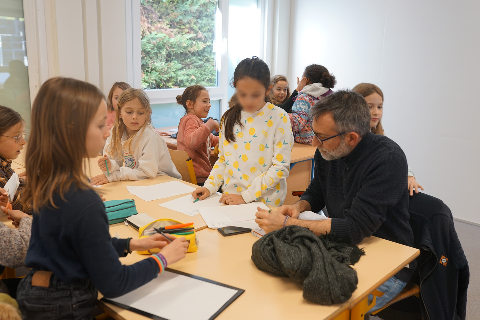 Un professeur accompagne des élèves dans la réalisation de leur devoir.