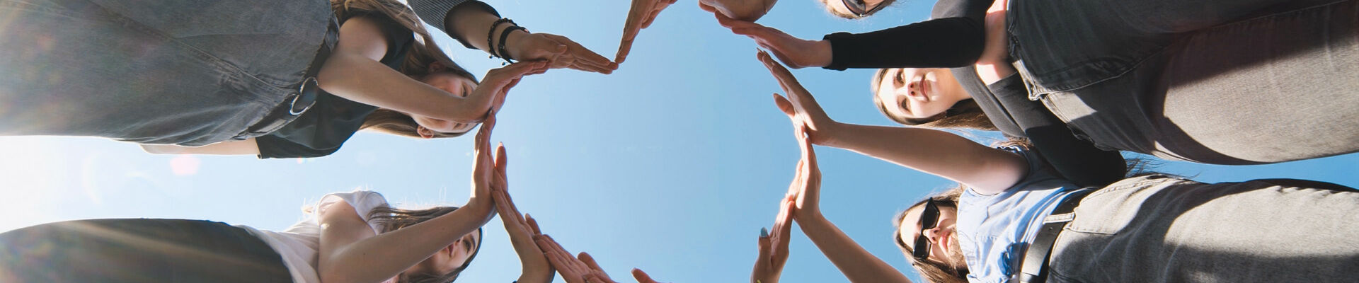 Un groupe de personnes sont en cercle et forment un cœur avec leurs bras.