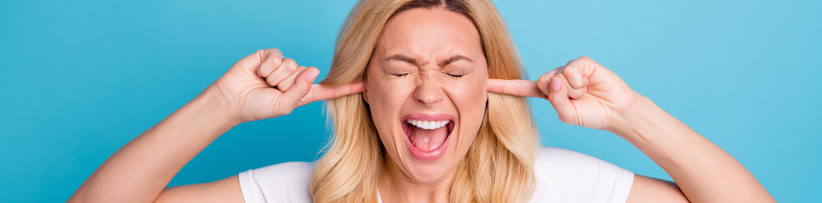 Une femme se bouche les oreilles à cause de la règlementation du bruit qui n'est pas respectée par un professionnel ou un particulier.