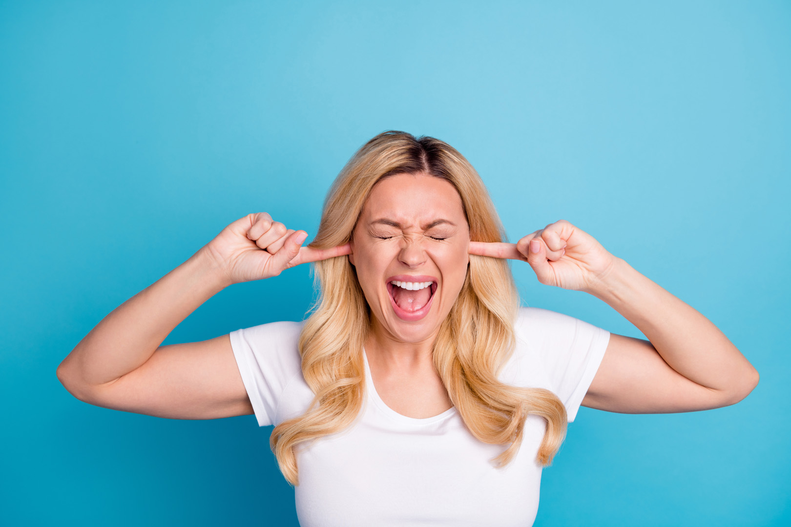 Une femme se bouche les oreilles à cause de la règlementation du bruit qui n'est pas respectée par un professionnel ou un particulier.