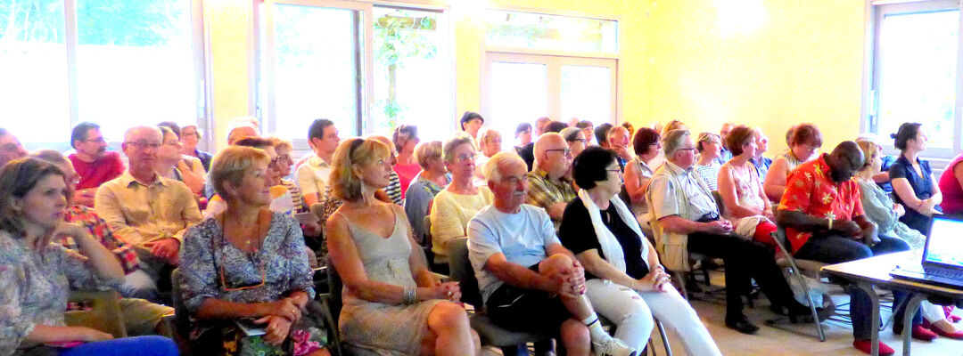 Un groupe de personnes assissent dans une salle communale pour participer au comité de quartier.