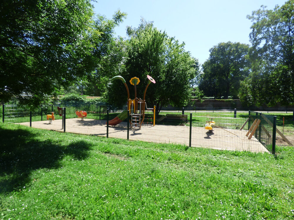 Une photo prise à l'extérieur de l'aire de jeu du parc de la jonchère avec un toboggan et des jeux à bascule. 