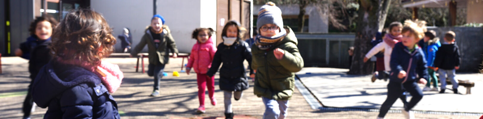 Des enfants dans joue dans la cour de récréation lors du temps périscolaire en maternelle.