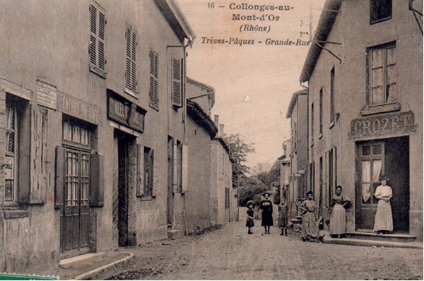 Une ancienne photo de là des commerces de Collonges au Mont d'Or. Des personnes posent devant les façades de magasin.