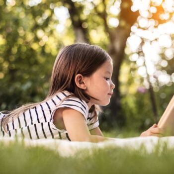 vue sur une enfant en train de lire un livre dans la nature