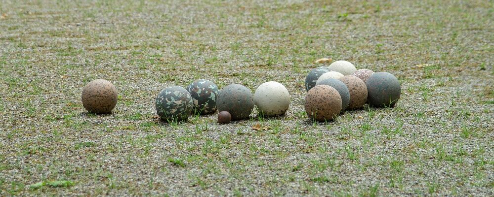 Boules en pierre et un petit cochonnet en bois sur le terrain de pétanque enherbé