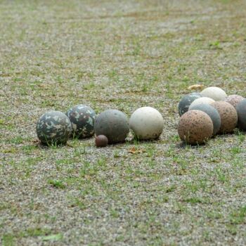 Boules en pierre et un petit cochonnet en bois sur le terrain de pétanque enherbé